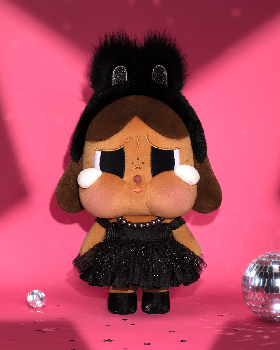 Plush toy with black hat and skirt on a pink background with disco balls