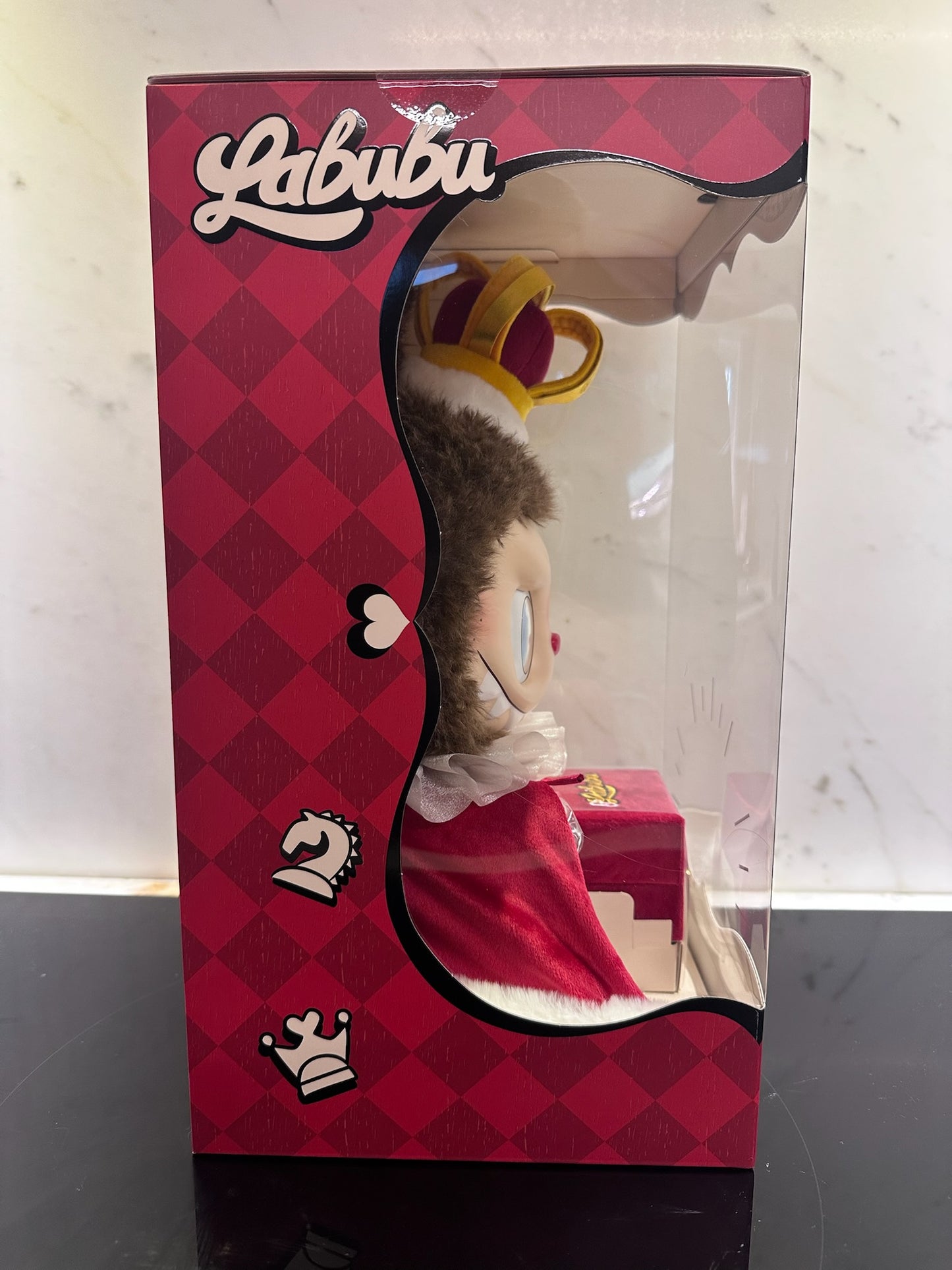 Labubu toy packaging with a checkered pattern and toy peeking out.