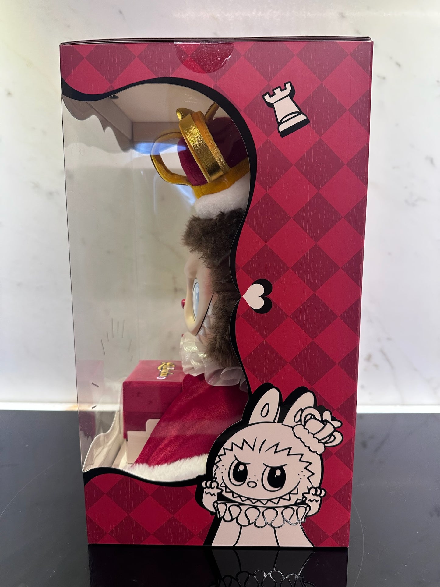 Toy figure in a decorative box with a red and pink checkered pattern