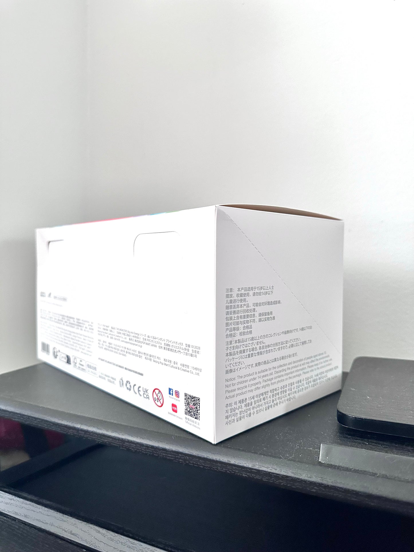 White box with text and QR code on a gray surface