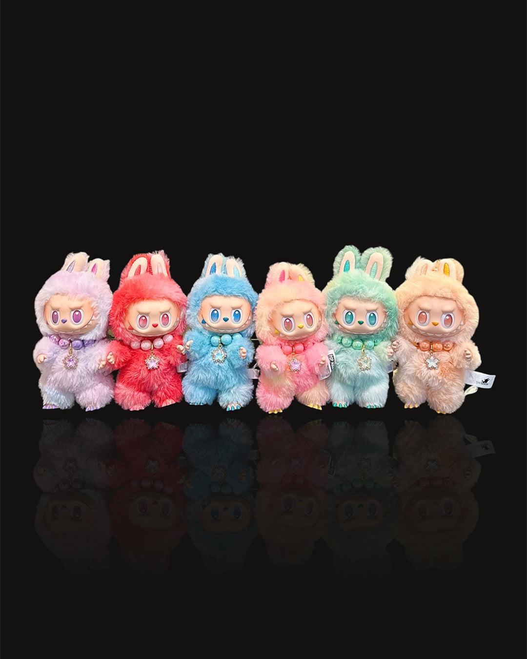 Set of colorful plush toys with bunny ears on a black background