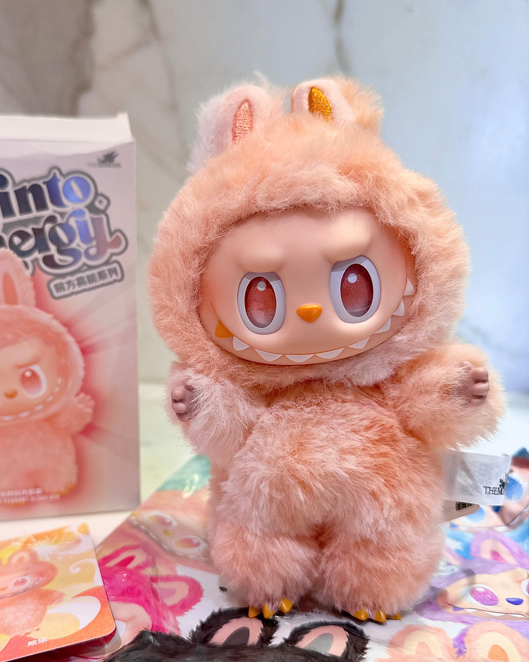 Plush toy with a cute design in front of a product box