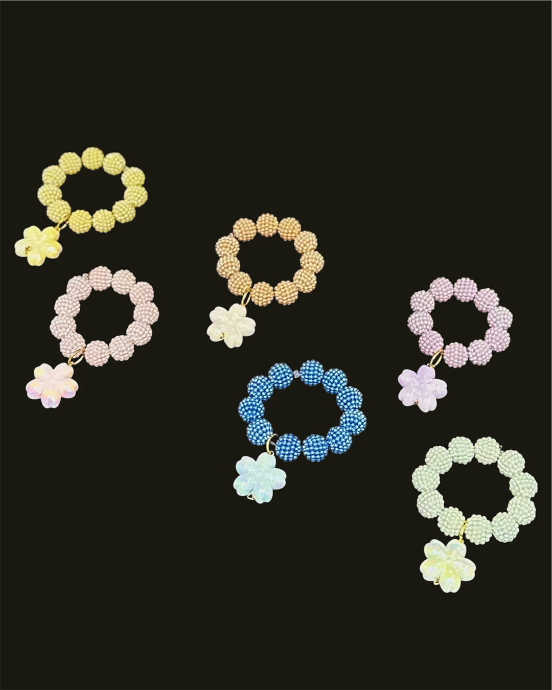 Set of colorful beaded bracelets with floral charms on a black background