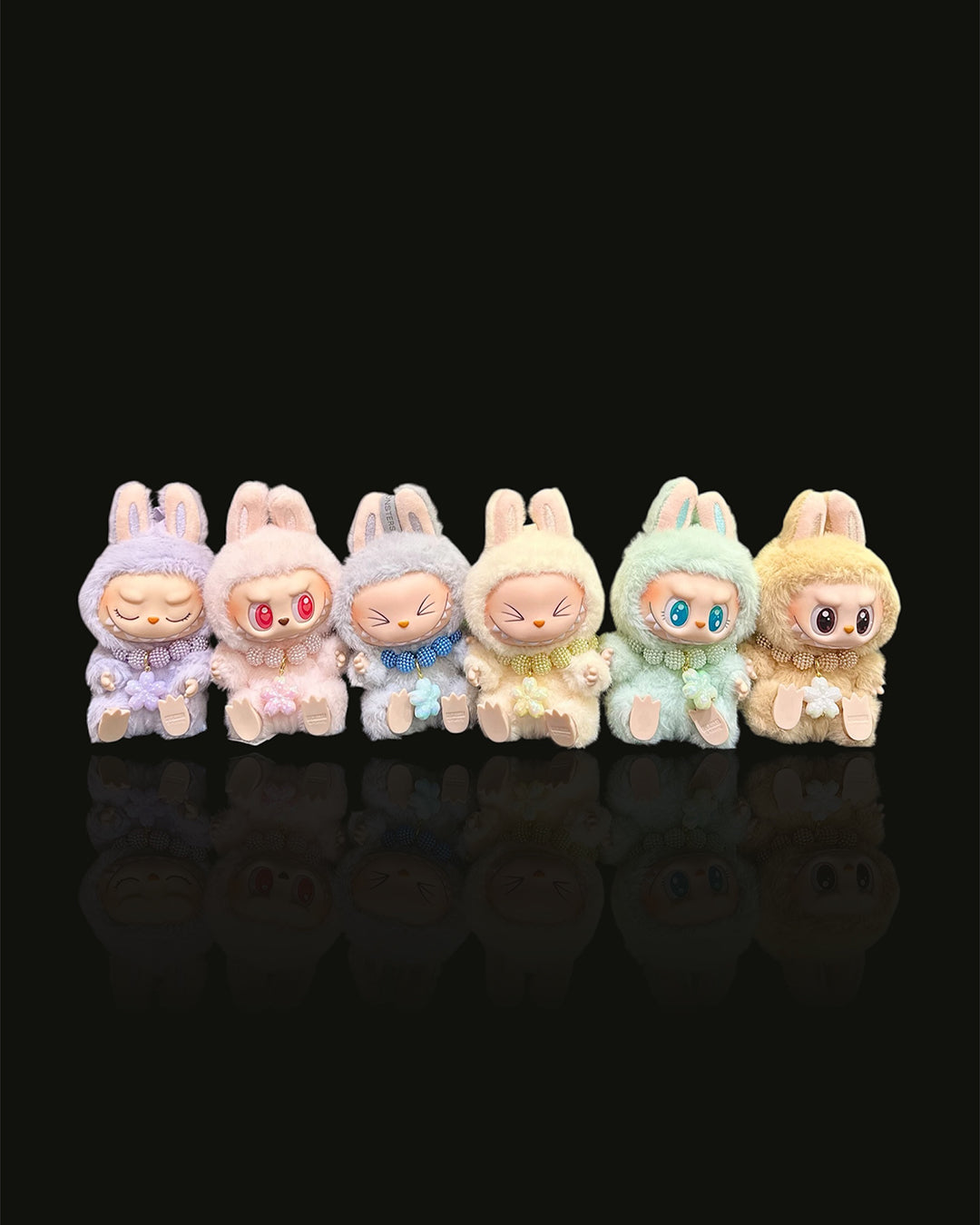 Set of six colorful plush toys with different expressions on a black background