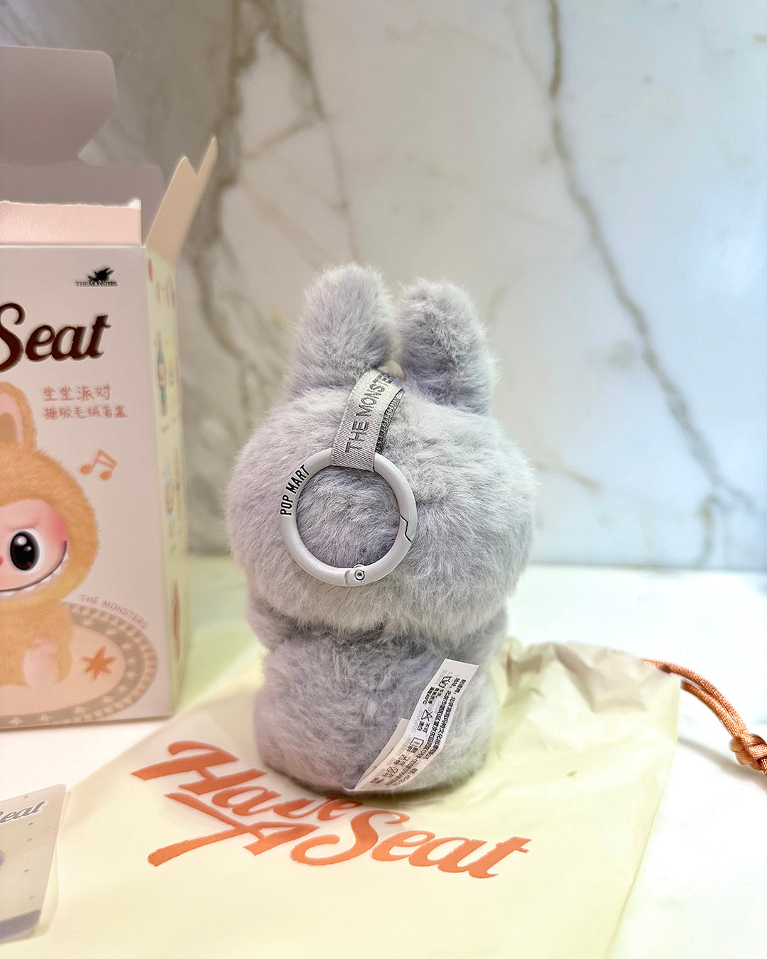 Gray plush toy with a white ring on a blurred background