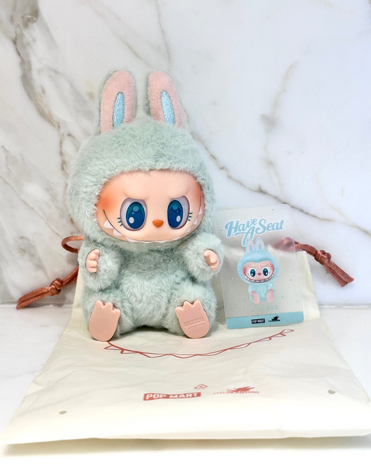 Plush toy with bunny ears and a small bag with branding on a white background