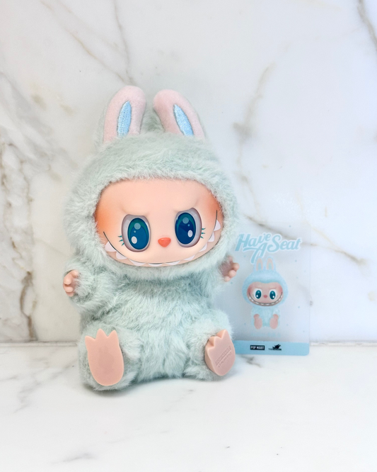 Plush toy in a bunny costume with a small plush toy in the background on a white surface.