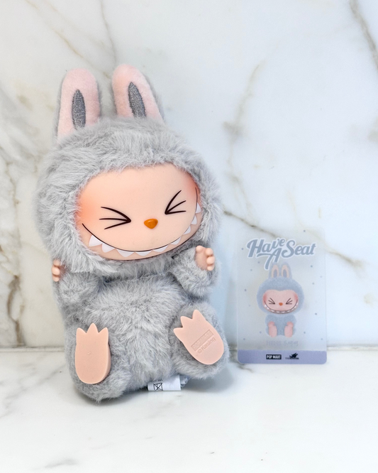Gray plush toy with bunny ears and a package labeled 'Hug A Seal' on a white background