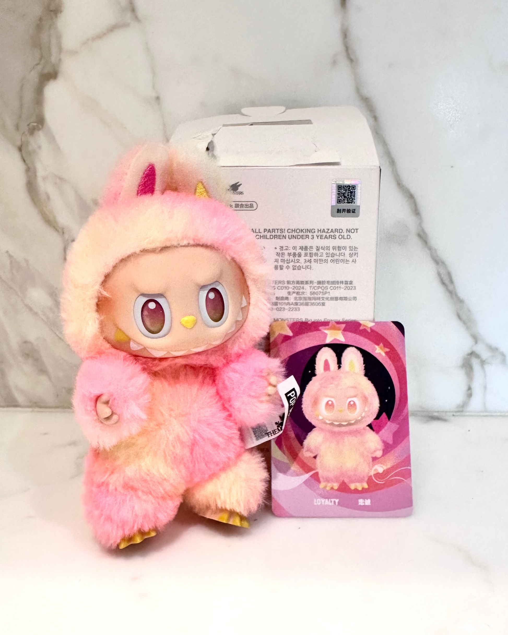 Pink plush toy with packaging on a light background