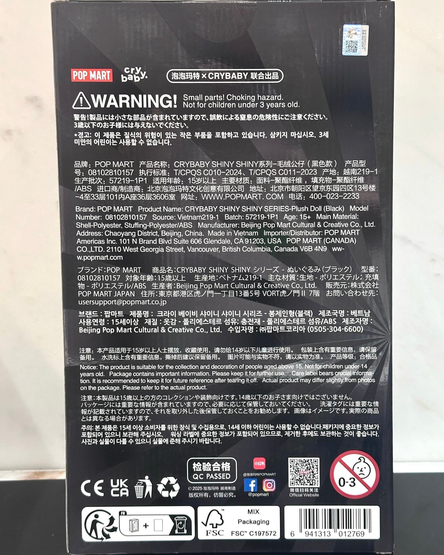 Back of a toy packaging with text, symbols, and branding on a white background