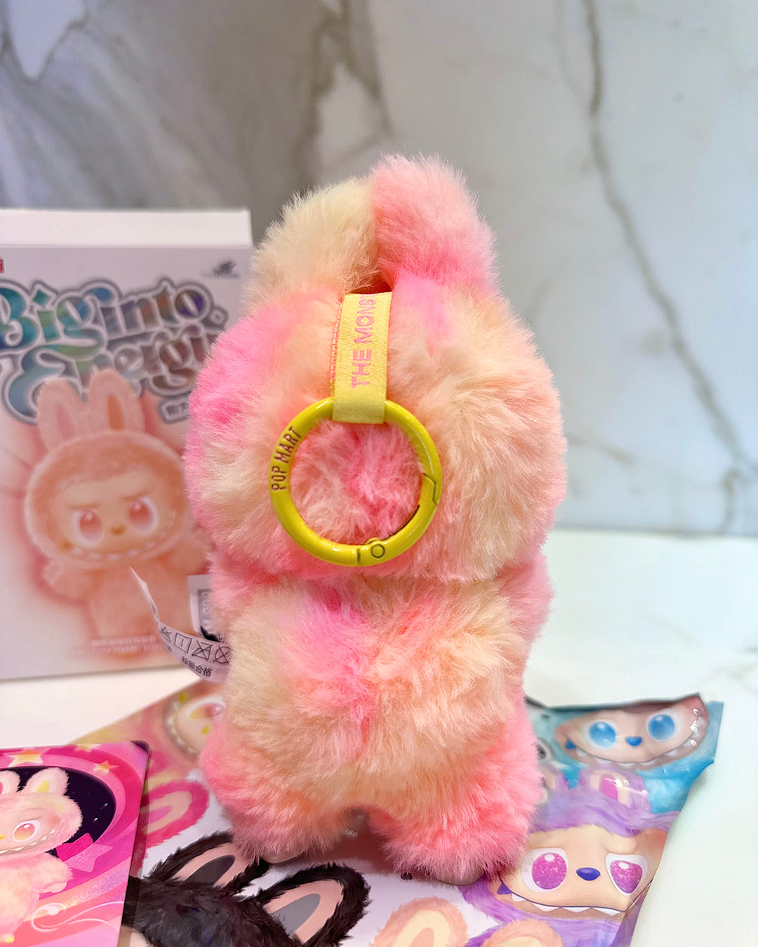 Plush toy with a yellow ring on a white surface with cartoon-themed items.