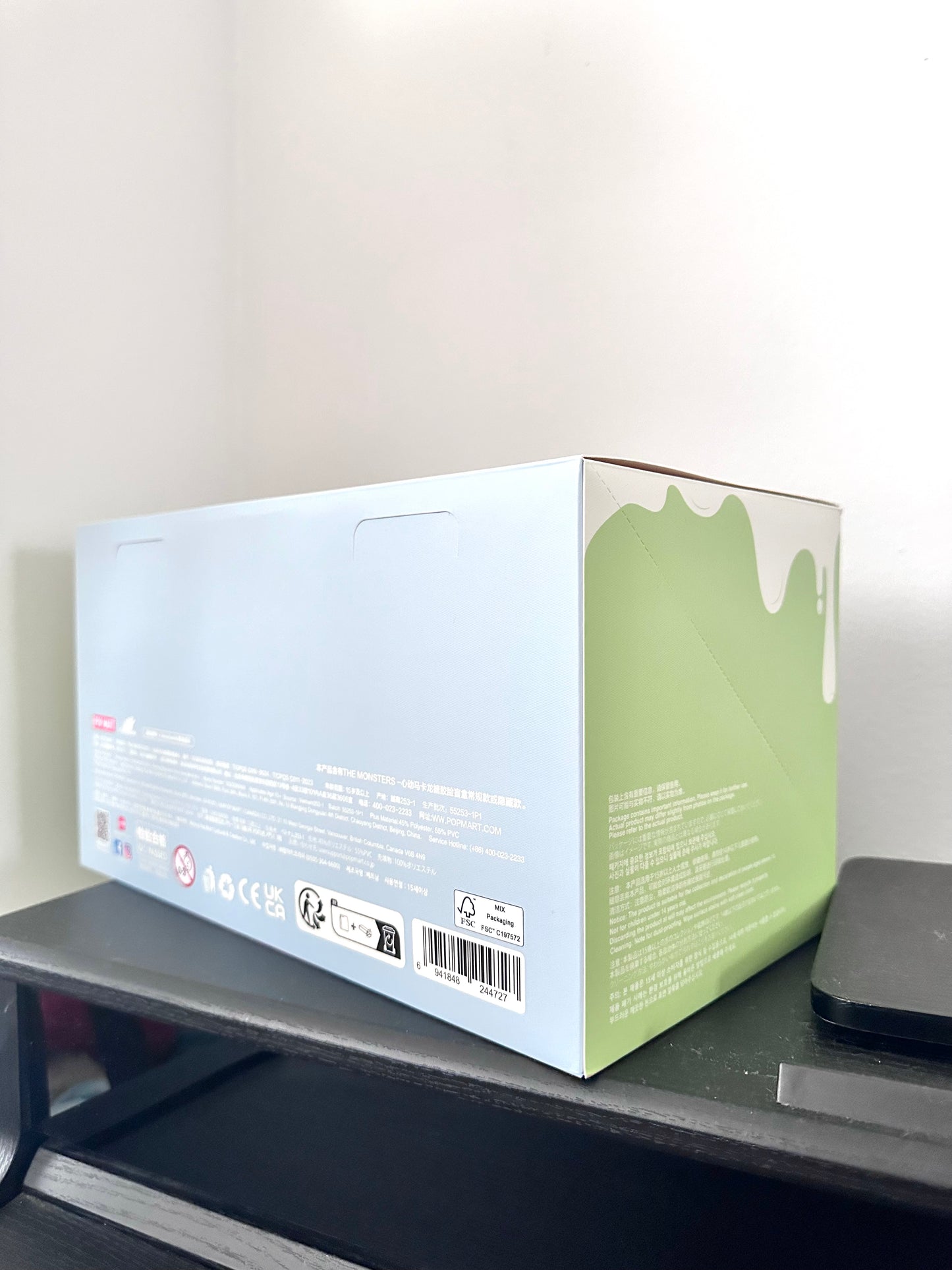 White and green box on a black surface with a light gray background