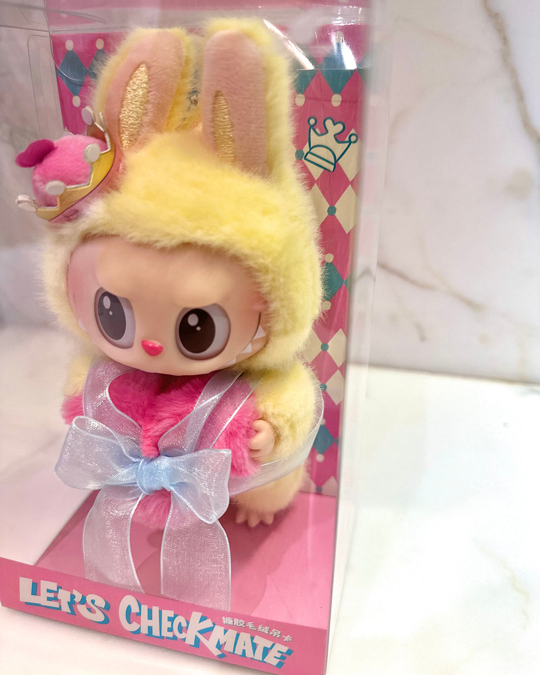 Toy figure with bunny ears and pink outfit on a colorful box