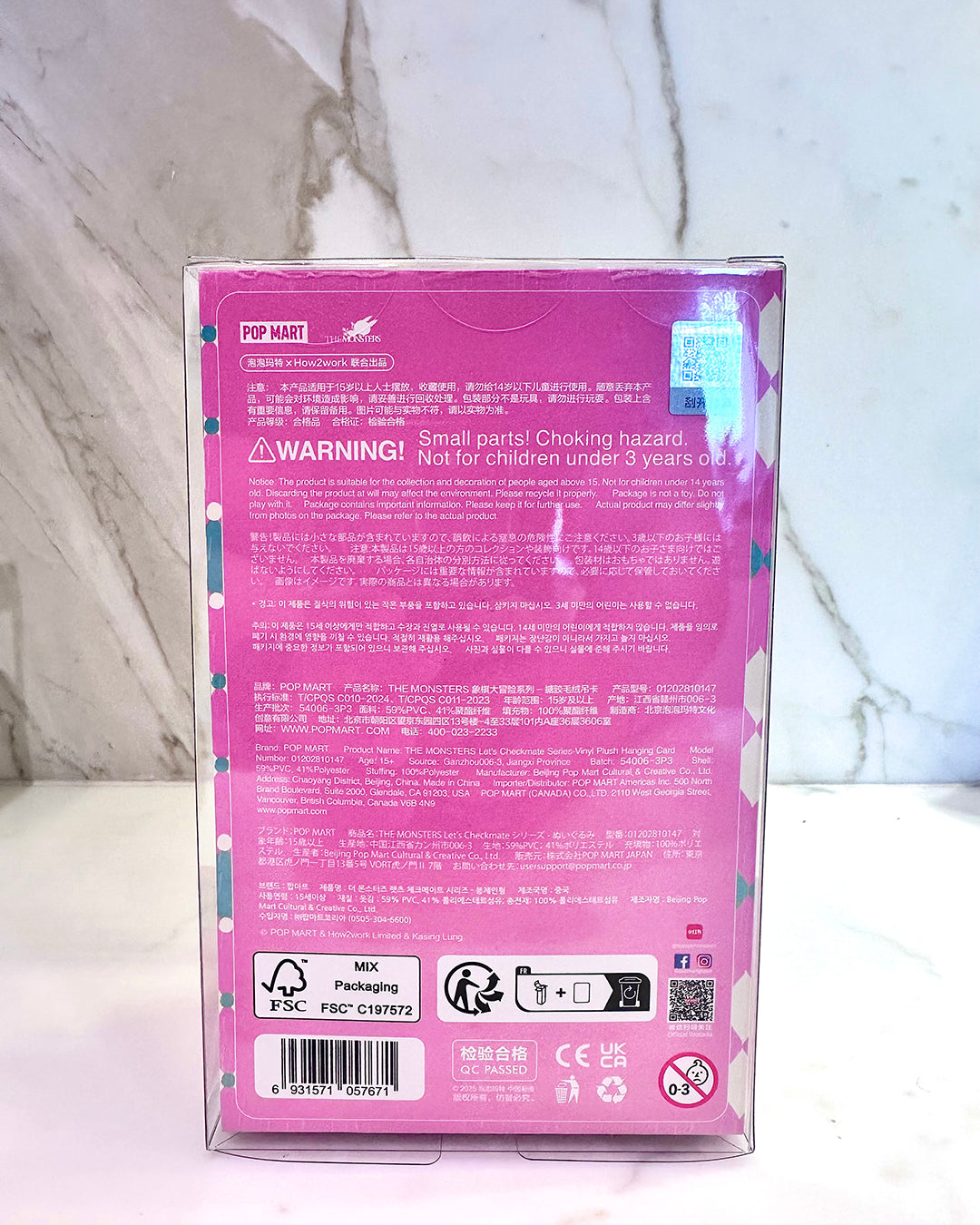 Pink toy packaging with warning label on a marble surface