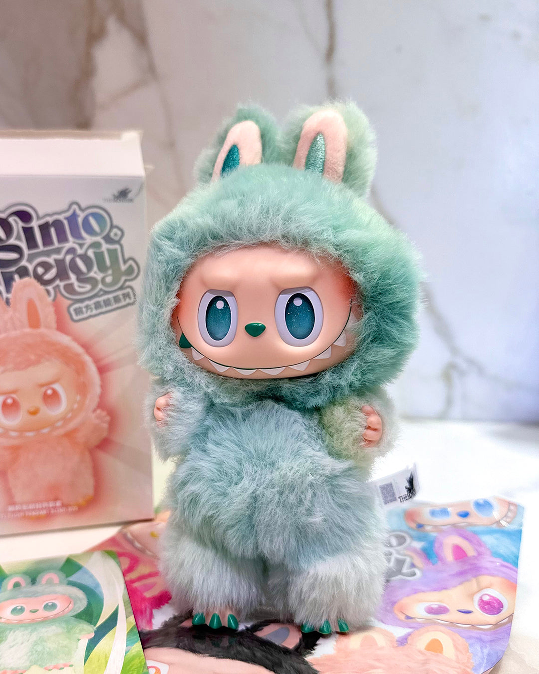 Toy figure in a green hood with bunny ears on a white surface
