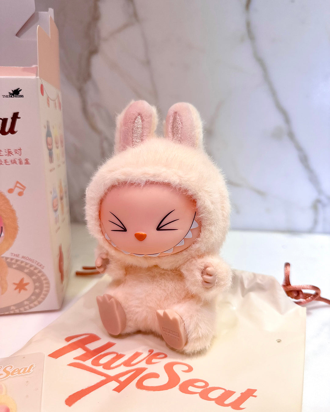 Plush toy with rabbit ears on a white surface with 'Have Seat' branding.