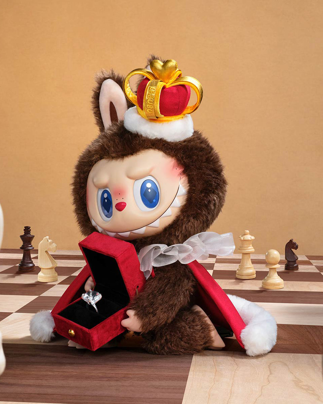 Stuffed toy with a crown and open red box on a chessboard