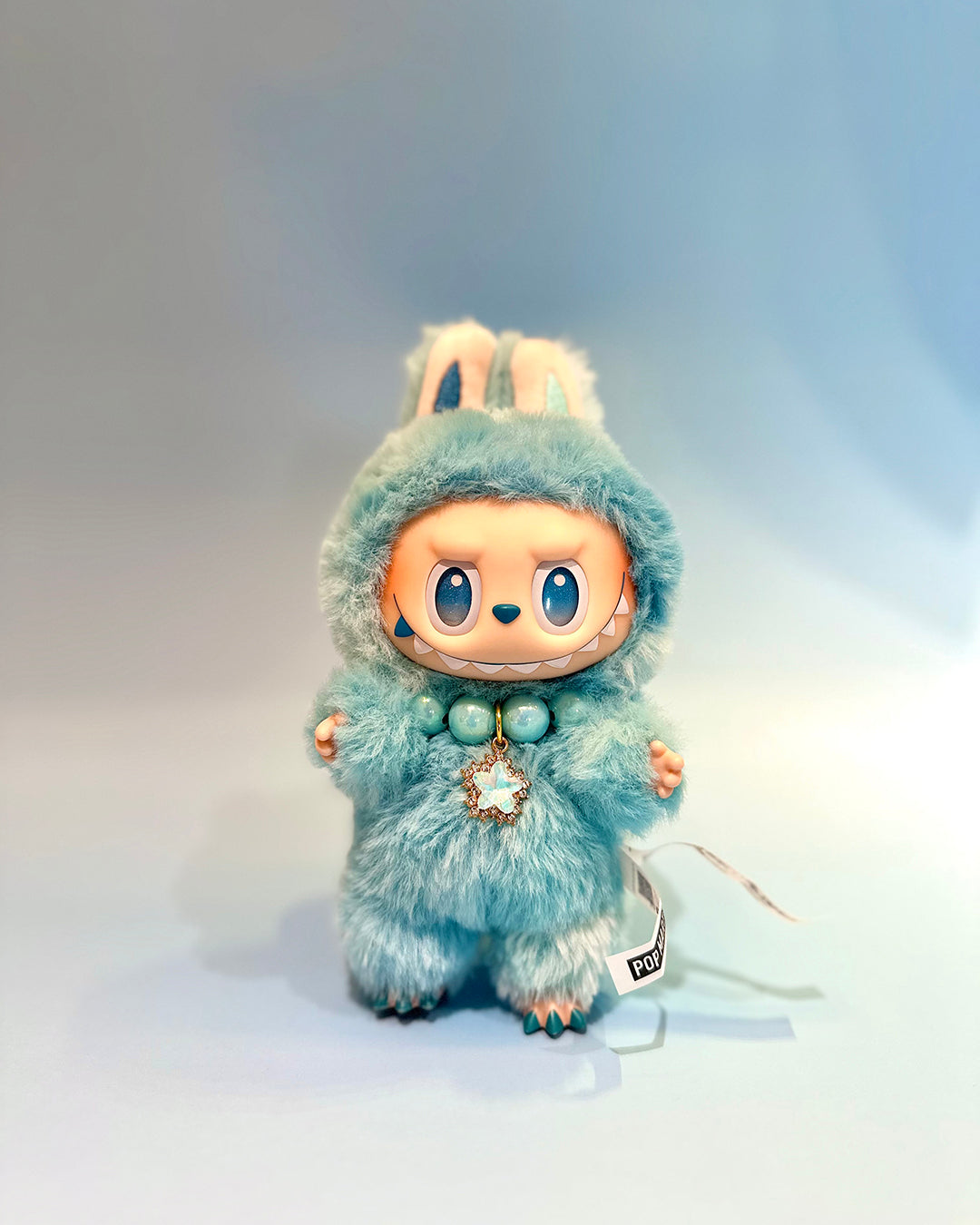 Toy figure in a blue fluffy outfit with bunny ears on a light gray background