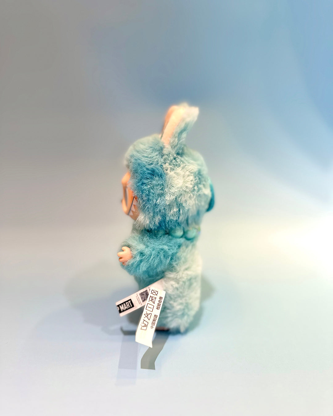 Plush toy with a tag on a gradient gray background