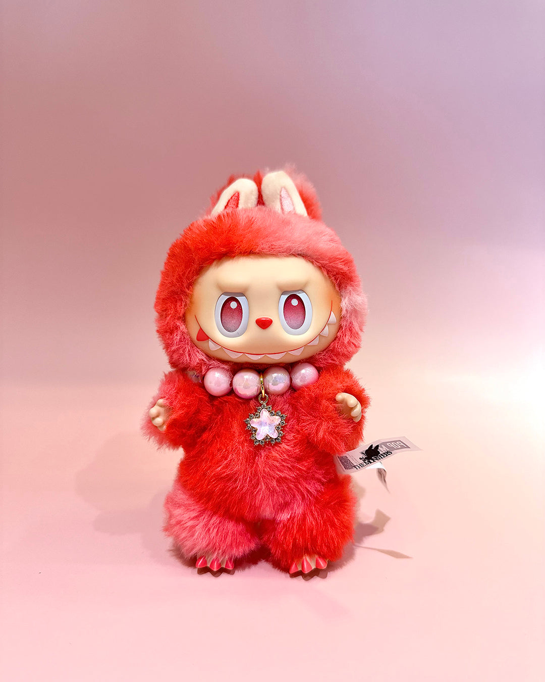 Red plush toy with a fluffy texture on a pink background