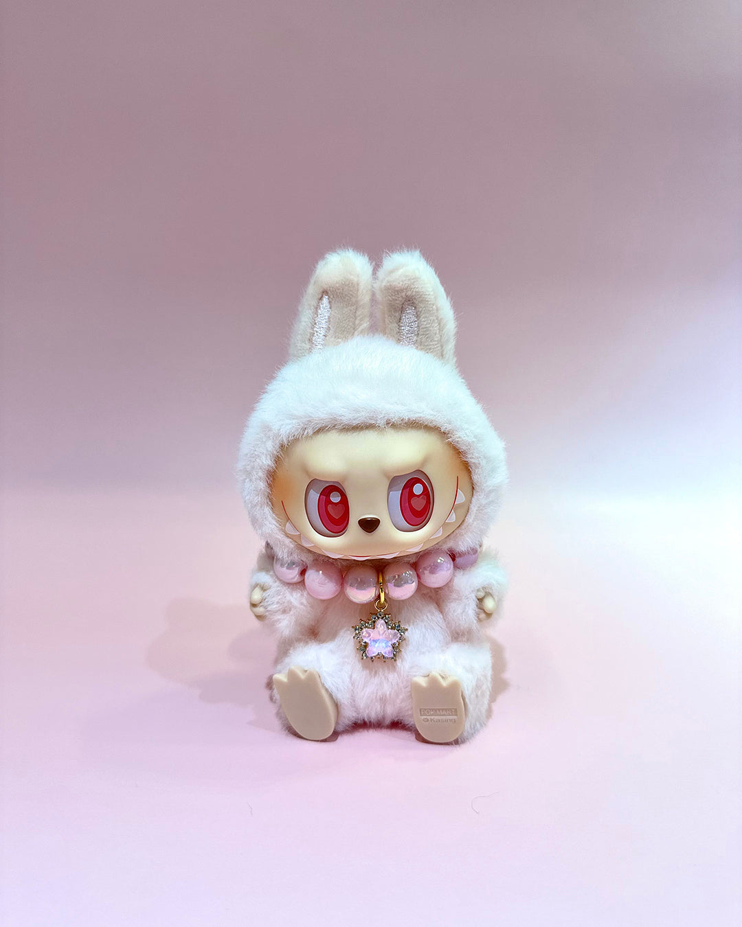White plush toy with bunny ears and red eyes on a pink background