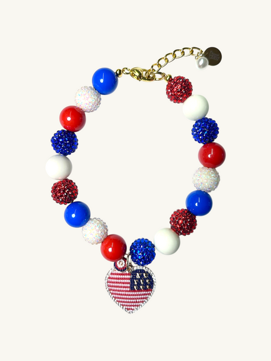 A pet luxury beaded necklace handmade in New York City in red, white, and blue with heart charm as part of The Haus Royale's The Americana collection