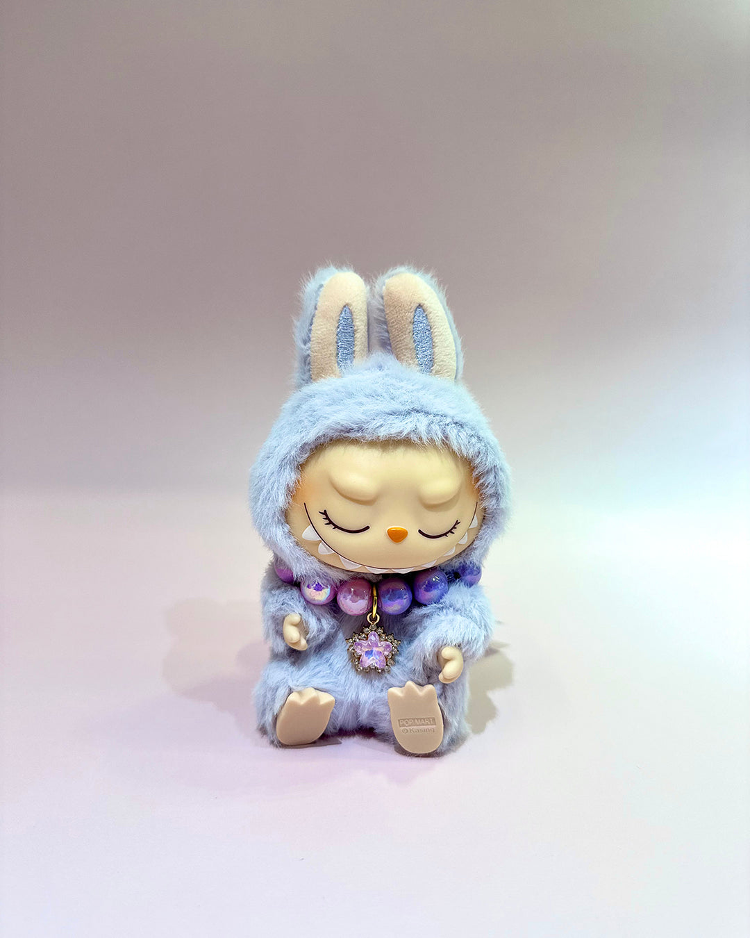 Plush toy with a blue hood and rabbit ears on a light gray background