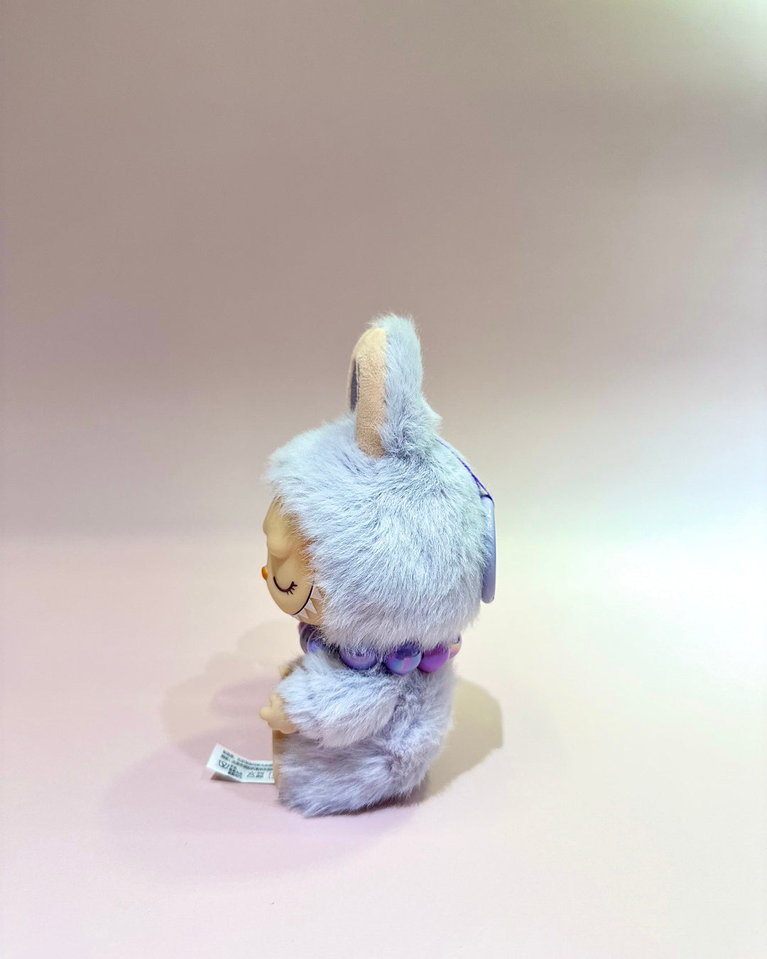 Plush toy with a fluffy gray hood on a beige background
