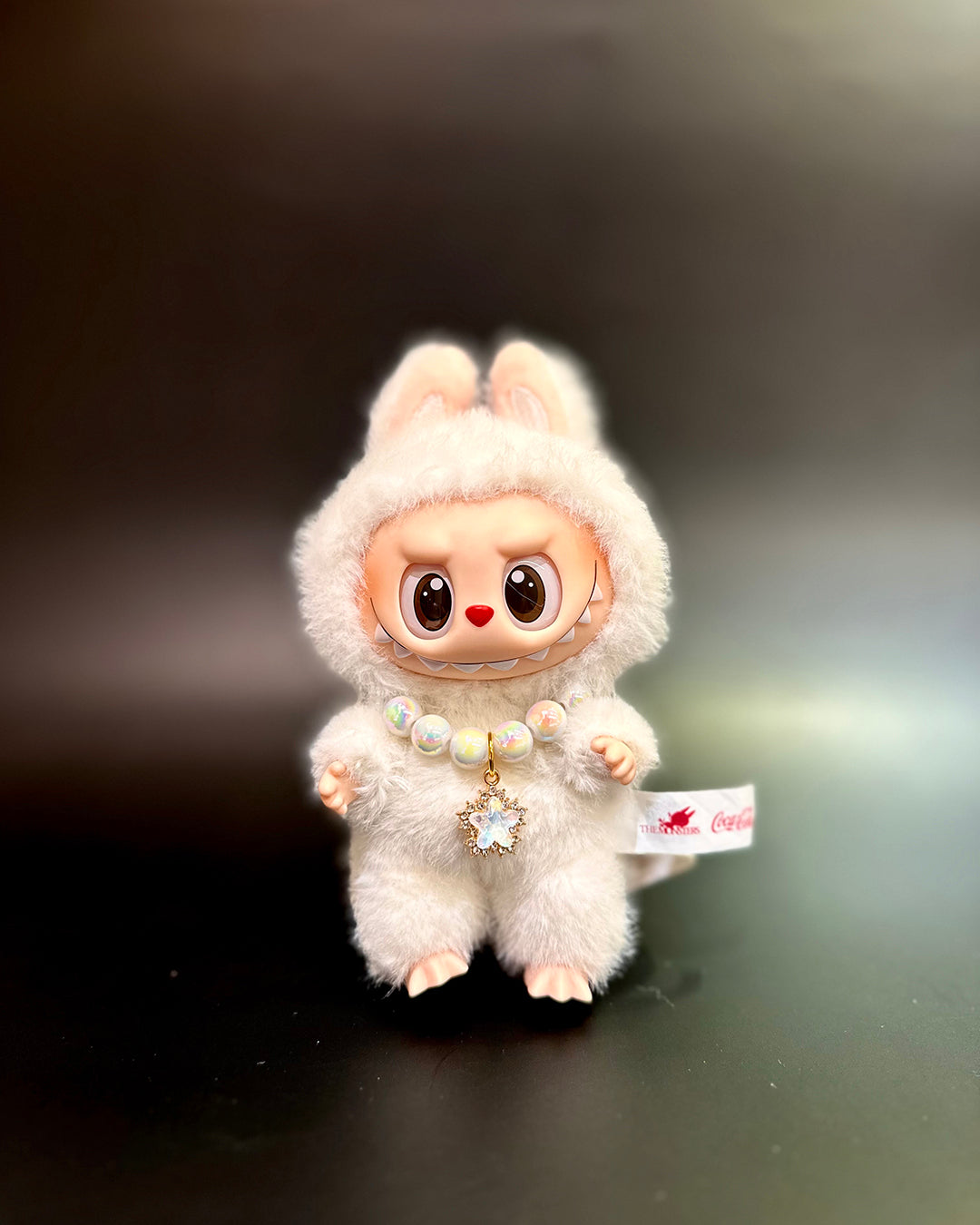 White fluffy toy with a tag on a dark background