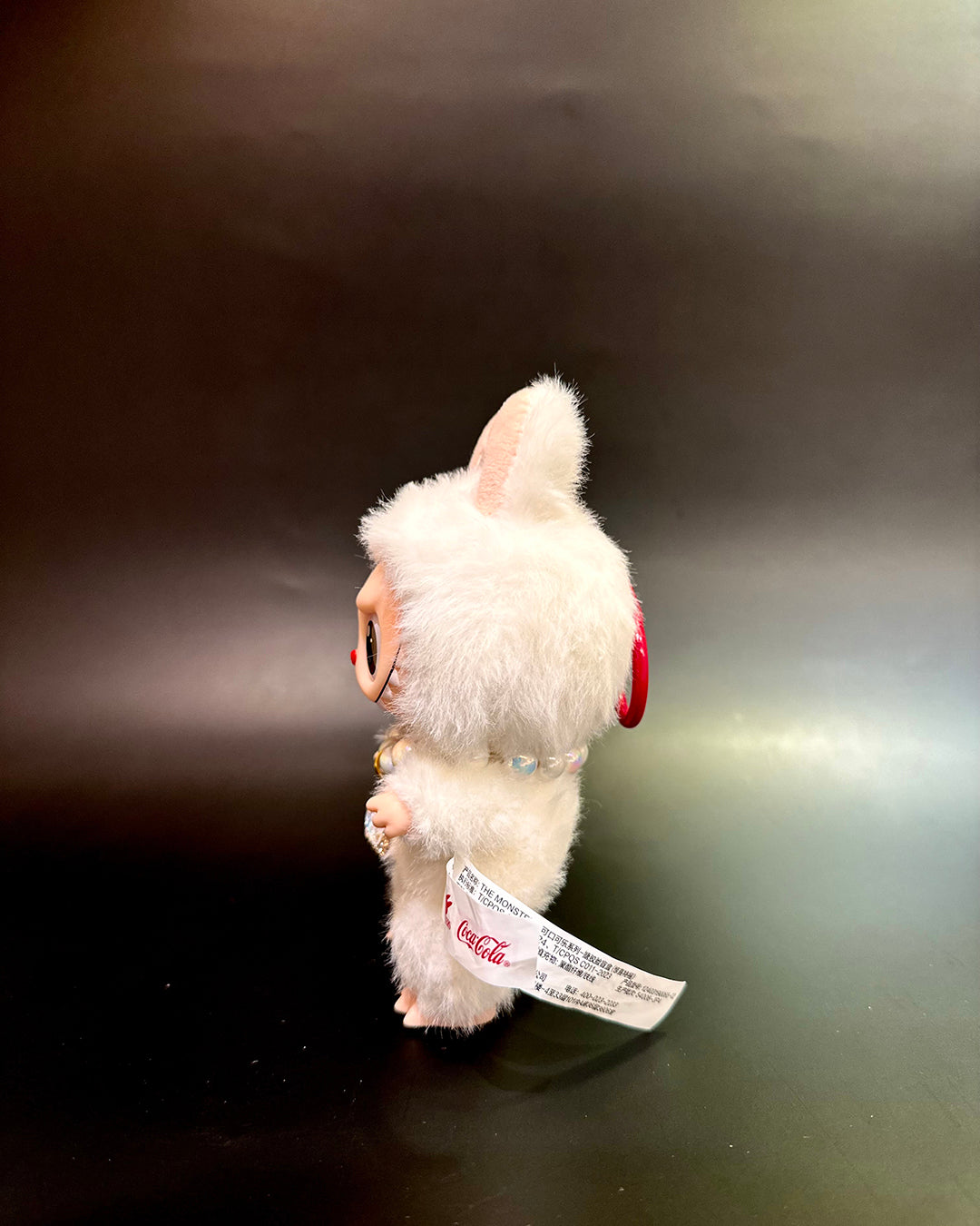 White plush toy with red accents on a dark surface