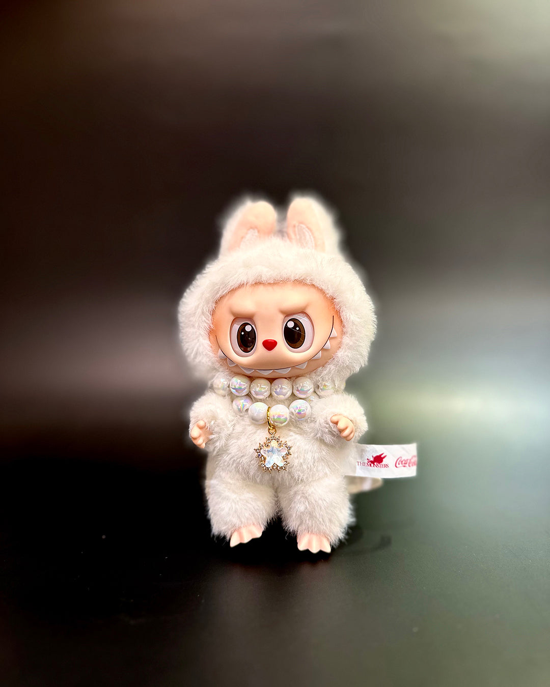 White plush toy with a fluffy hood on a dark background