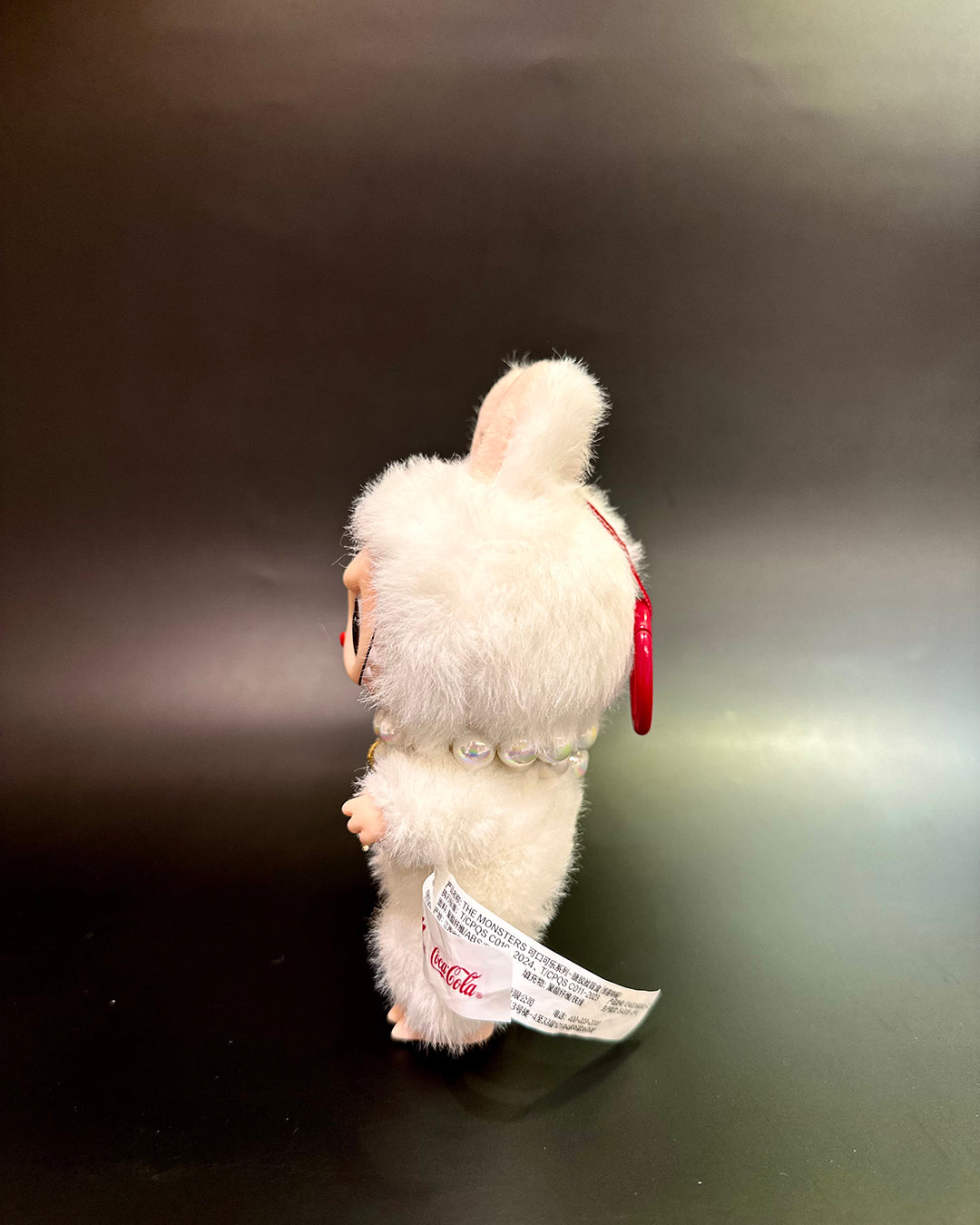 White plush toy with a red tag on a dark background
