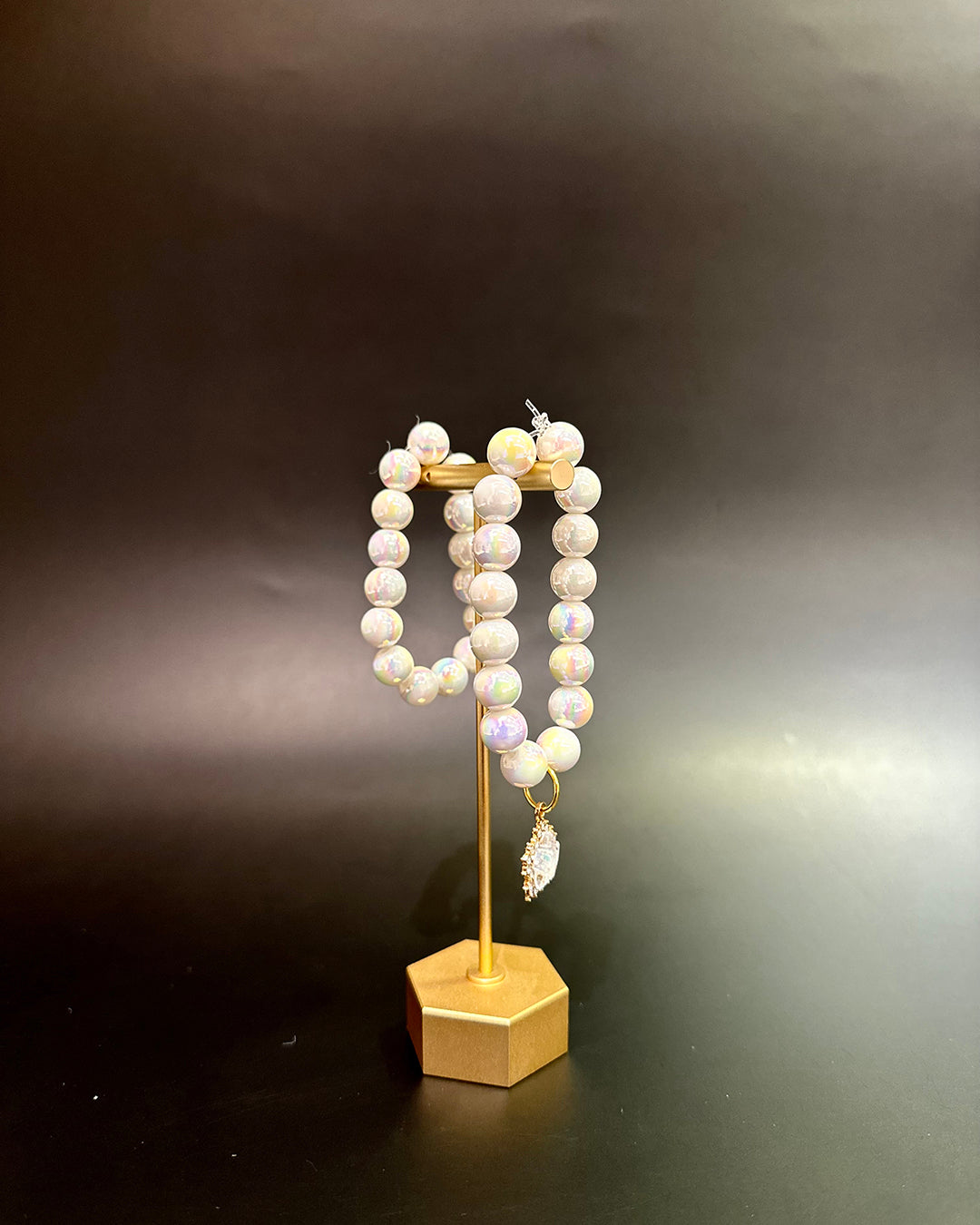 Pearl bracelet on a gold stand against a dark background