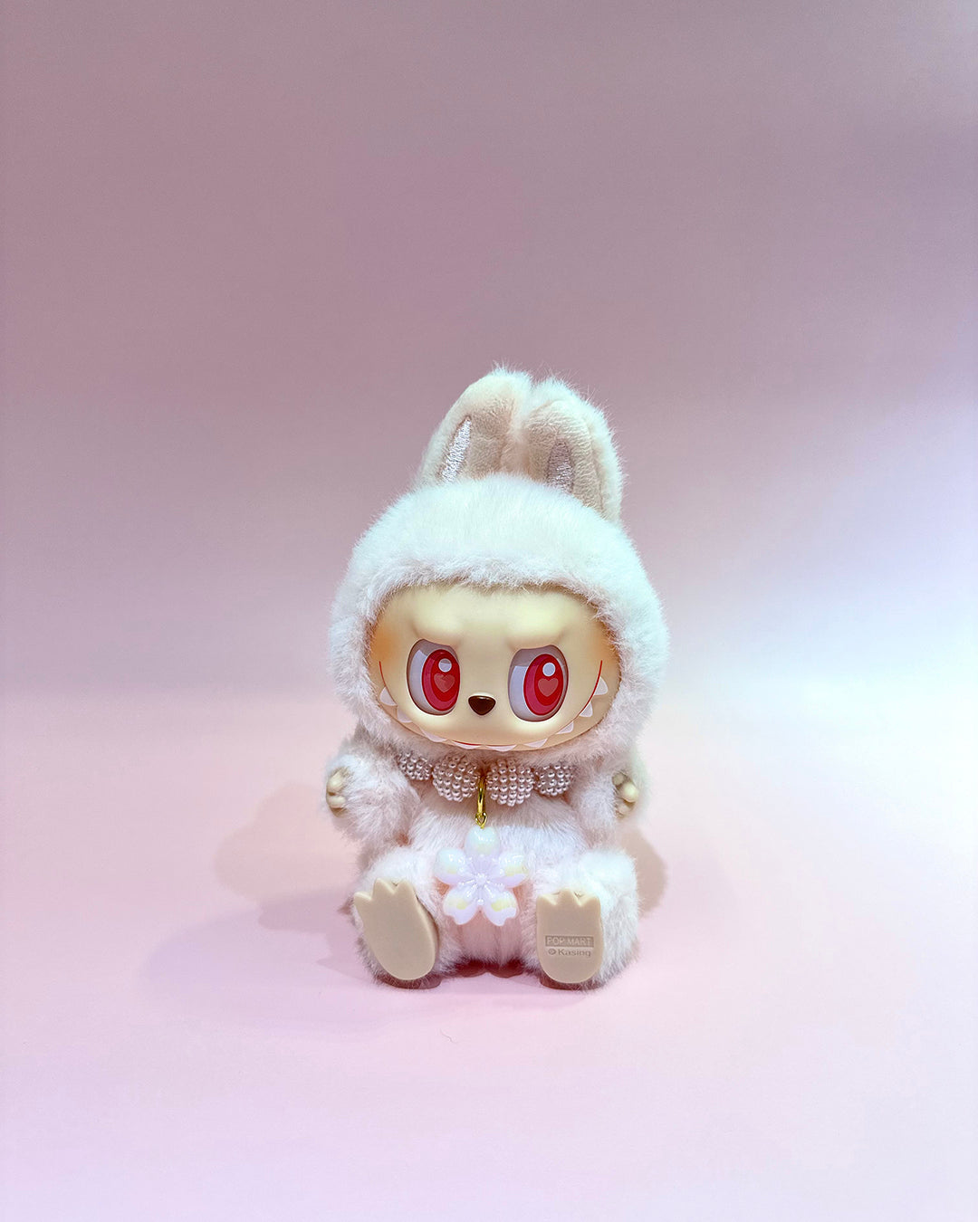 Stuffed animal toy with bunny ears and red eyes on a pink background
