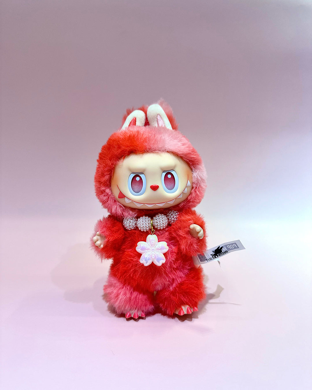 Plush toy with red fur and bunny ears on a light gray background