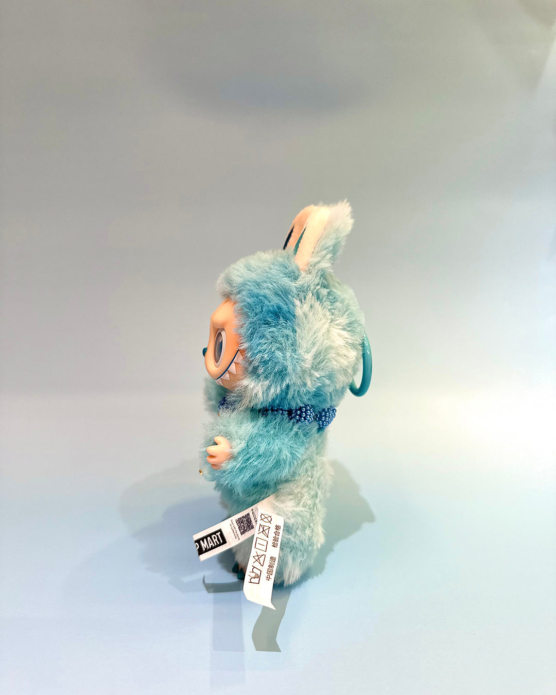 Plush toy with a blue fuzzy exterior and white interior on a light gray background