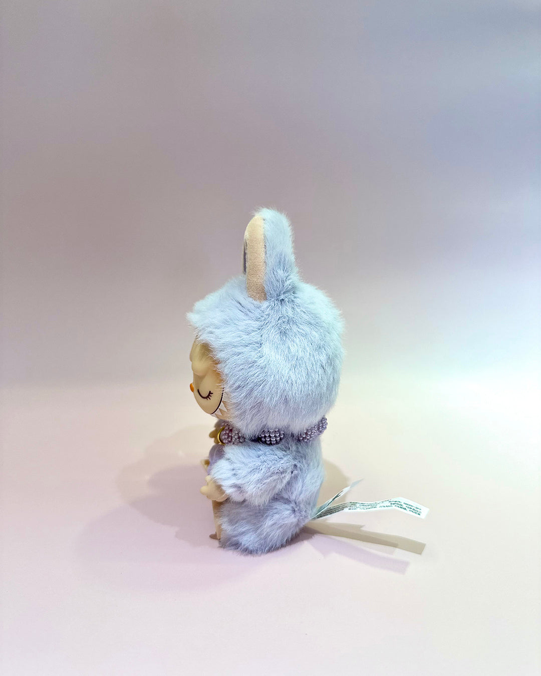 Small figurine with a fluffy blue hood on a plain background