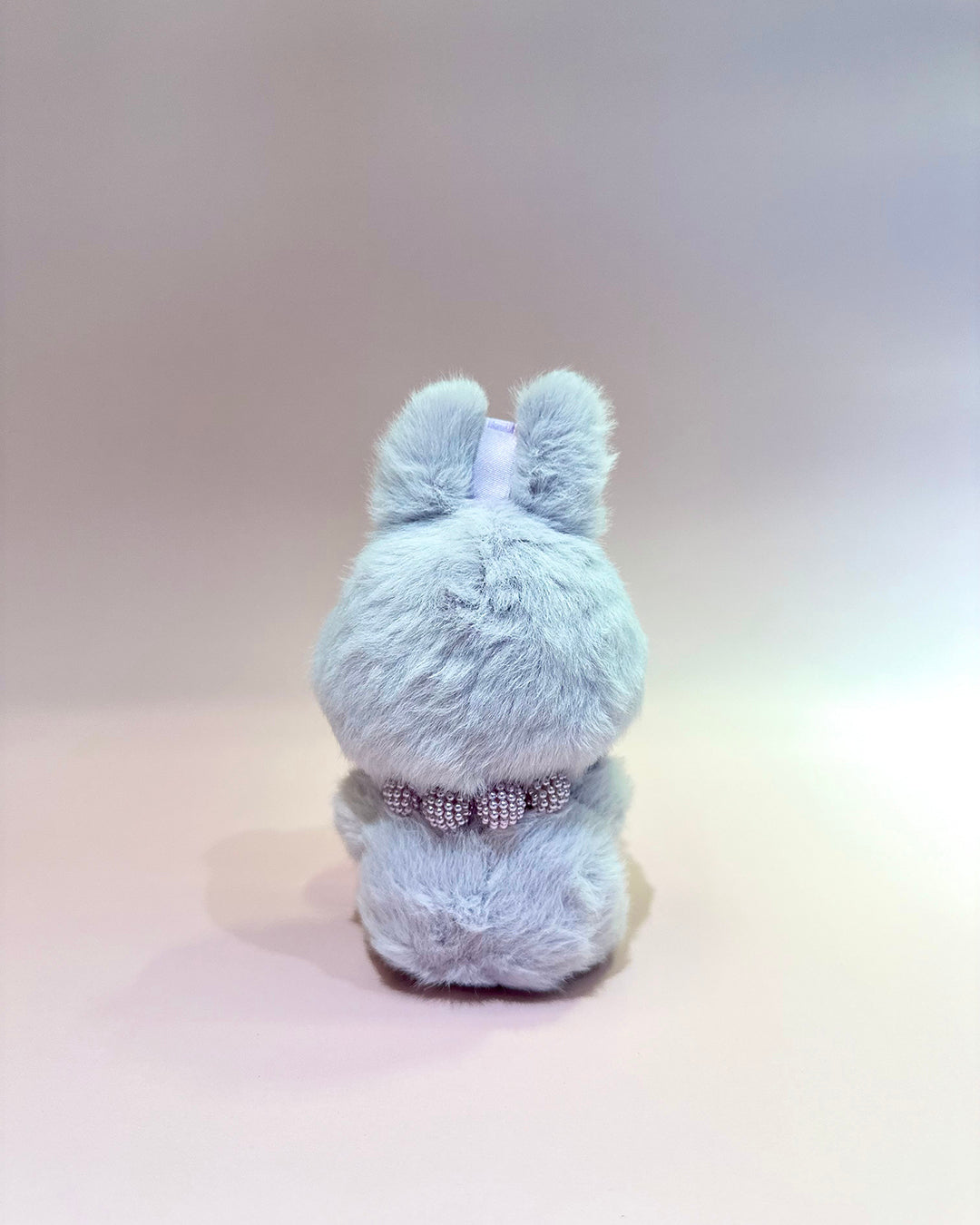 Light blue plush toy with a bow on a light gray background