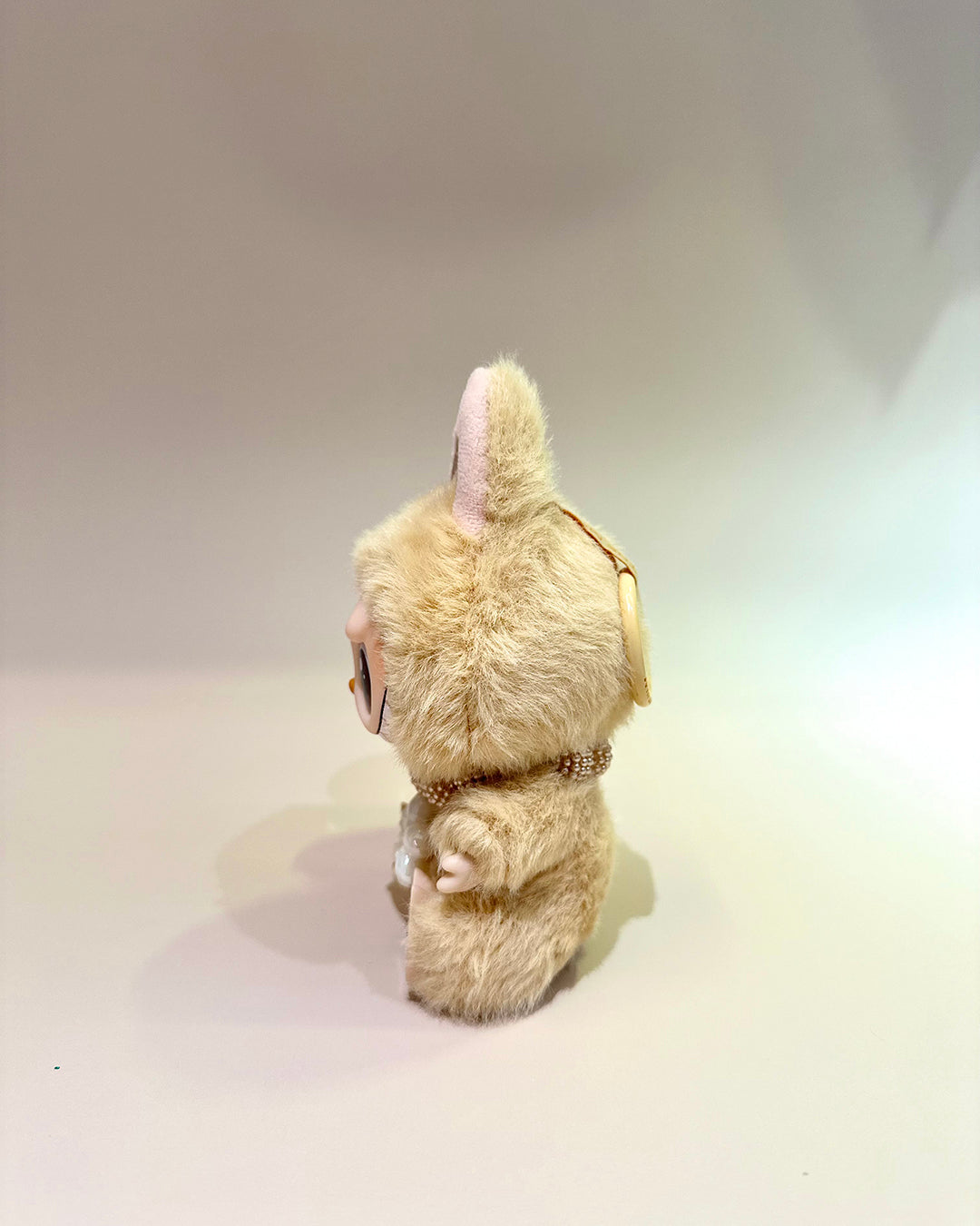 Plush toy resembling a rabbit with a pink bow on a plain background