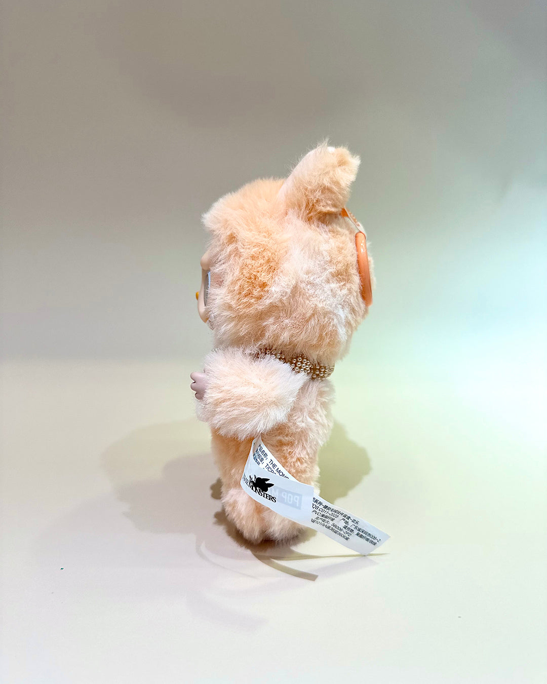 Small plush toy with a tag on a light background