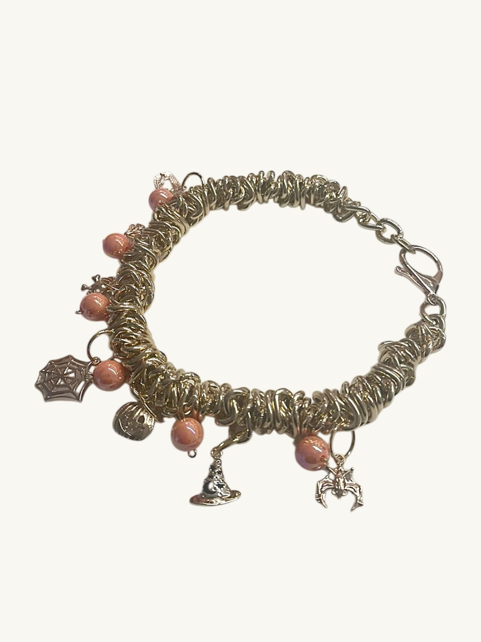 Bracelet with wire-wrapped design, pink beads, and charms on a white background