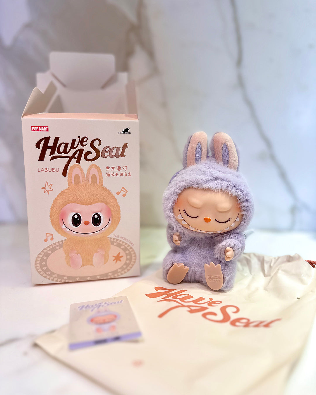 Plush toy in a costume next to packaging and a drawstring bag on a light background