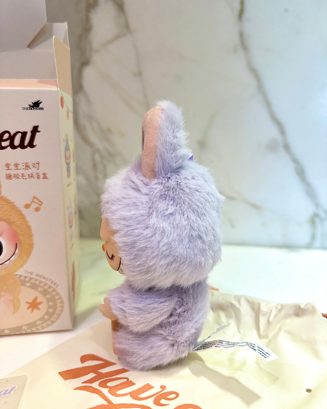 Plush toy resembling a rabbit next to a box with text on a light background