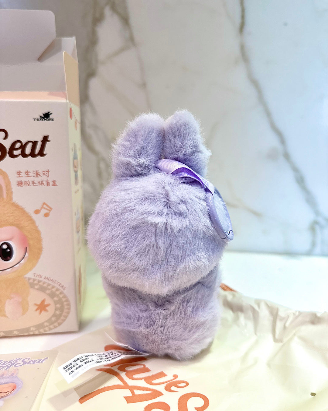 Plush toy with a bow and a box labeled 'Beat' on a light background