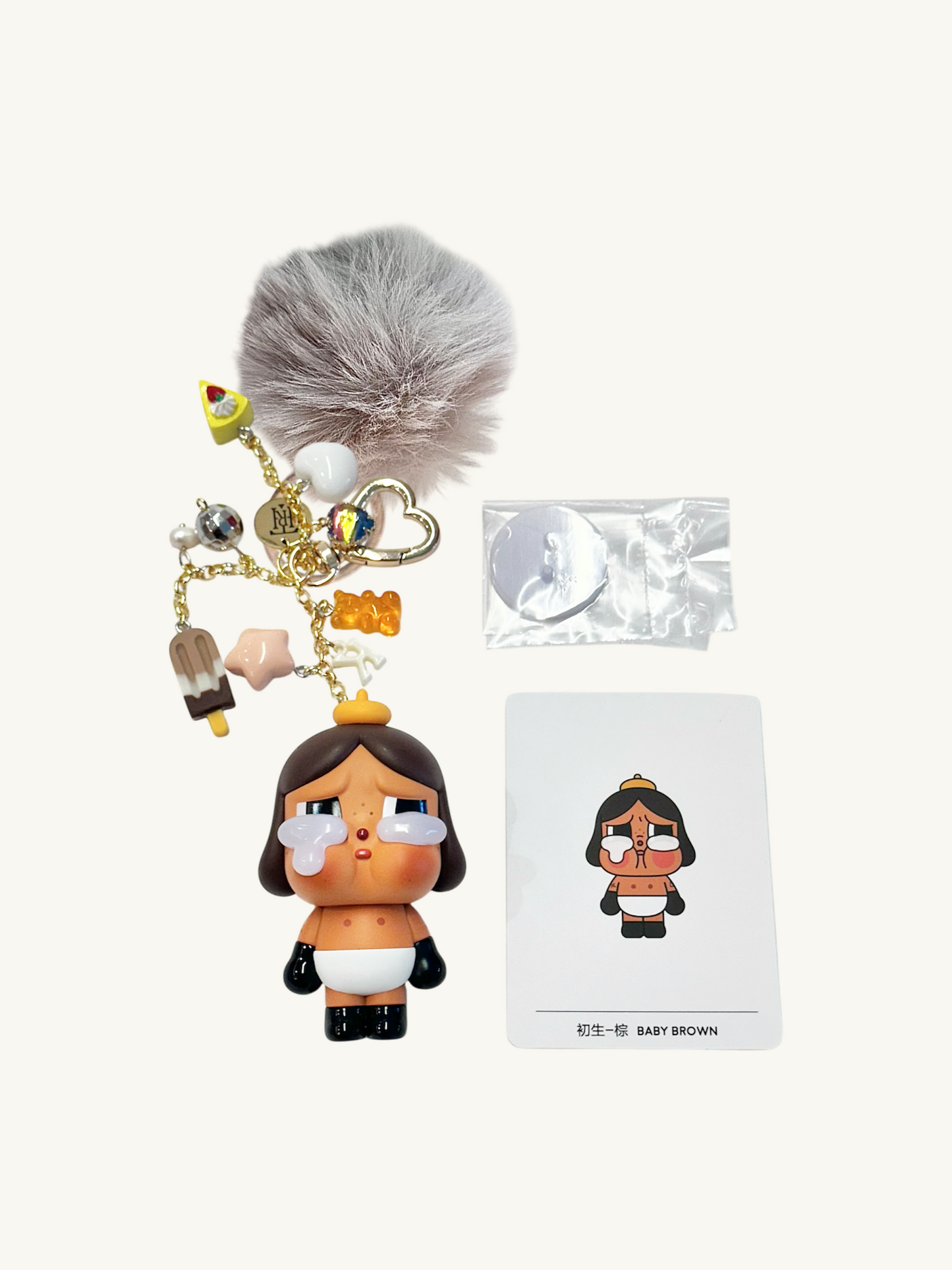 Keychain with character design, gray pom-pom, and packaging on a white background