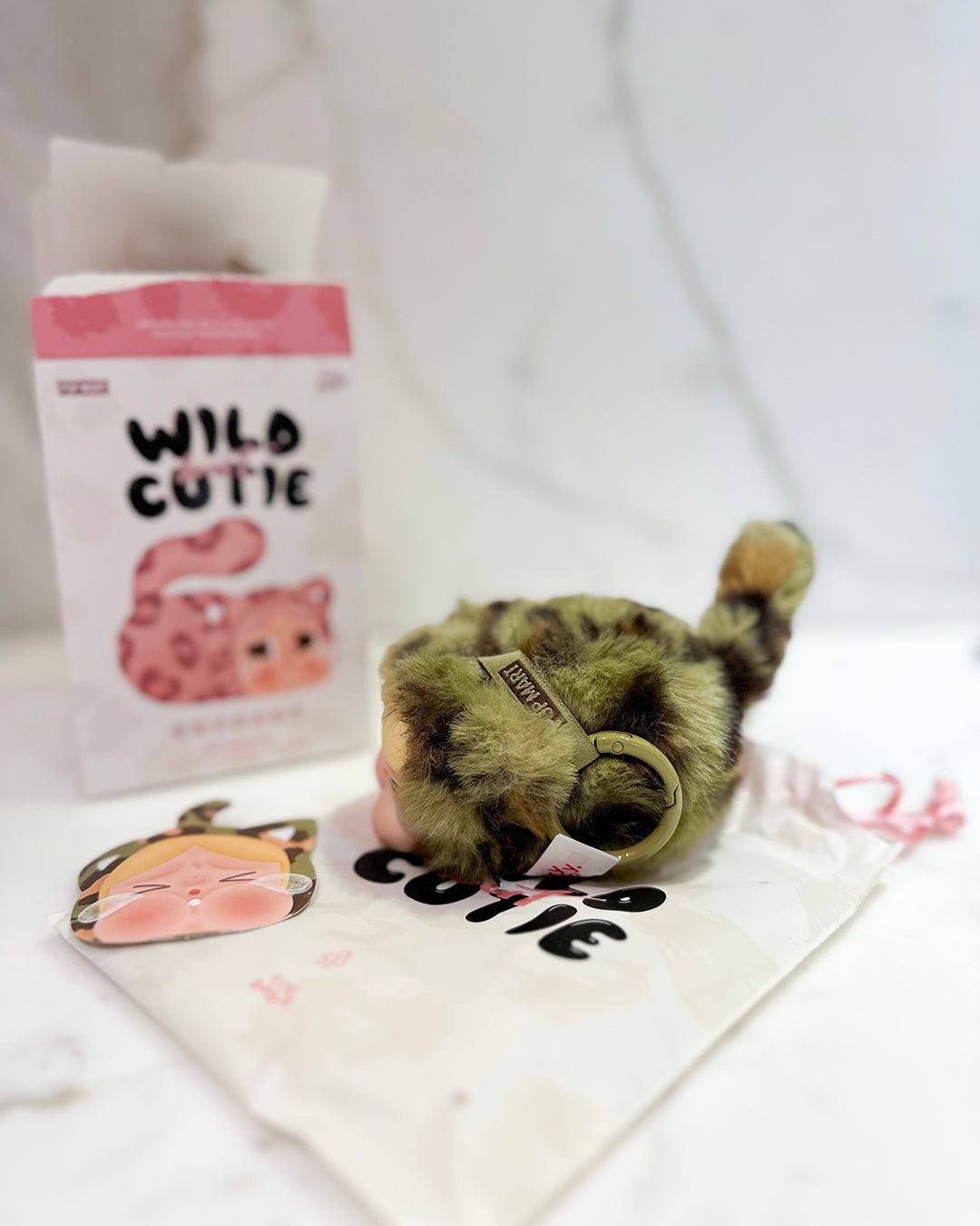 Plush toy raccoon with 'Wild Cutie' packaging and accessories on a white background