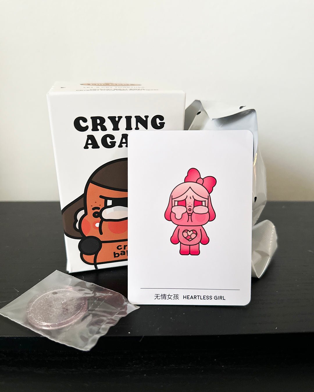 Card with a pink character and text 'Heartless Girl' on a black surface.