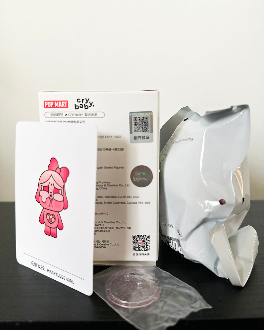 White mask with packaging featuring a pink character on a black surface