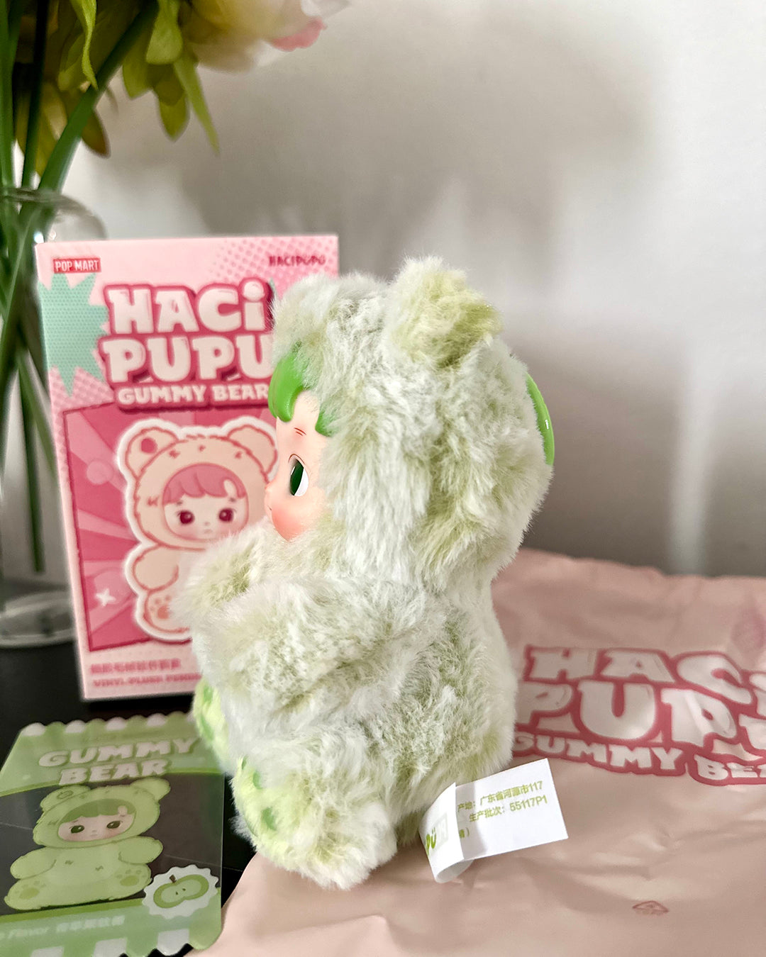 Green plush toy with a box of Haci Pupu gummy bears in the background