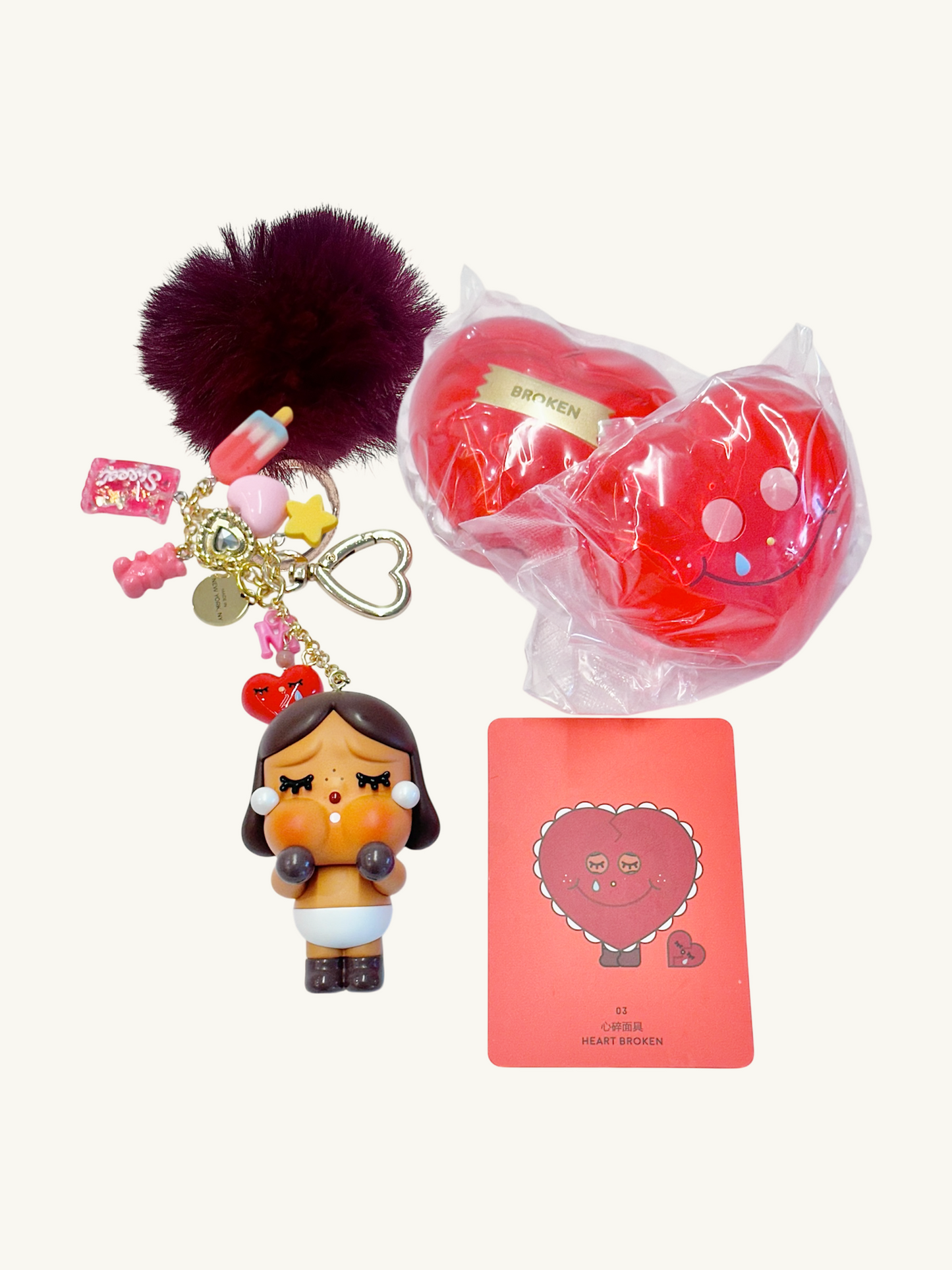 Keychain with cartoon character, red heart-shaped item, and pink card on a white background